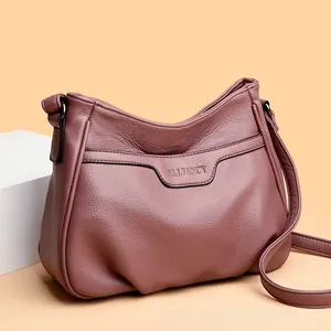 Detail of dusty pink pebbled leather shoulder bag with embossed logo on soft bag body