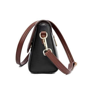 Black pebbled leather crossbody bag with brown strap and gold hardware side view