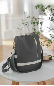 Vue détaillée du sac à dos antivol gris sur table avec une bandoulière courte offerte