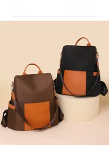 Detail view of two casual color-block backpacks in brown and black on a studio stand