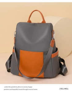 Detail of grey nylon backpack with orange leather contrast pocket and adjustable straps