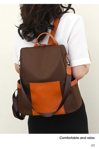 Detail of dark brown waterproof nylon backpack with orange leather trim on female model