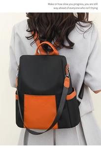 Detail of color-block backpack showing orange leather flap and black nylon texture