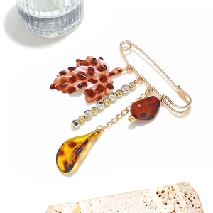 Broche feuille dorée rétro avec pendentif léopard et perles d'ambre sur fond blanc