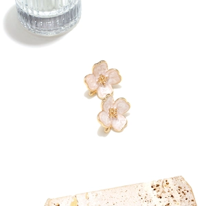 Close-up of pink enamel flower earrings with gold flower stamens on stone prop