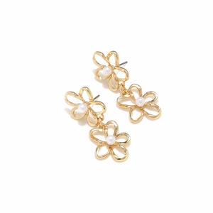 Close-up of golden hollow layered flower earrings with central pearls on white base