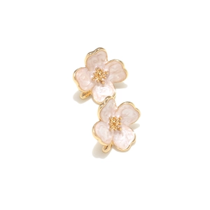 Detail of pink enamel flower earrings with golden metal edges and a soft shadow