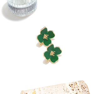 Detail of green enamel flower stud earrings with golden stamens on stone background