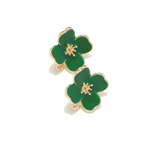 Close-up of green enamel flower earrings with gold-plated petals and floral metal base