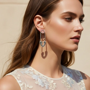 Silver safety pin earrings with hollow heart design worn by model in soft sunlight
