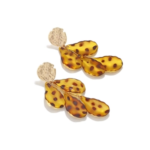 Close-up of leopard print resin leaves and hammered gold metal top on drop earrings