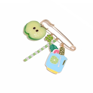 Detail of colorful fruit and wine glass pendants on a gold-tone safety pin brooch