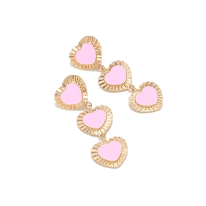 Dettaglio macro di orecchini a triplo cuore in oro con finitura smalto rosa chiaro