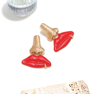 Boucles d'oreilles nez doré et lèvres émaillées rouges sur un support en pierre
