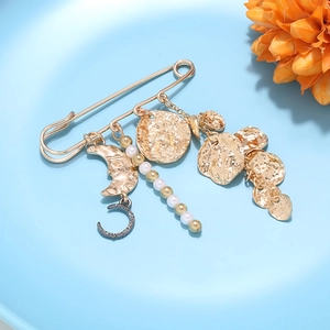Détail de broche épingle dorée vintage avec pendentif lune et pompon de perles