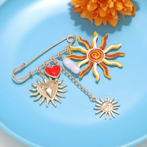 Detail of creative gold safety pin brooch with colorful enamel sun and heart charms