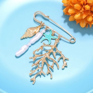 Détail de la broche corail avec perles baroques et étoile de mer sur épingle dorée