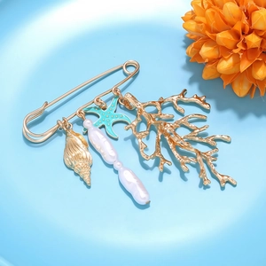 Détail d'une broche marine avec breloques d'étoile de mer, corail et perle baroque