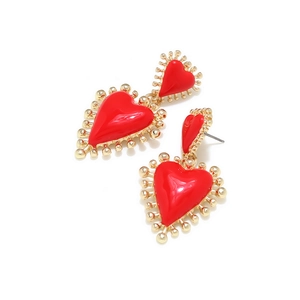 Detalle de pendientes de corazón en esmalte rojo con borde dorado y acabado de lujo