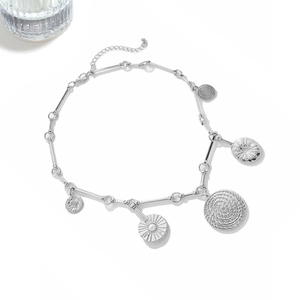 Detail of silver chain necklace with coin charms and sun pendants with pearl accents
