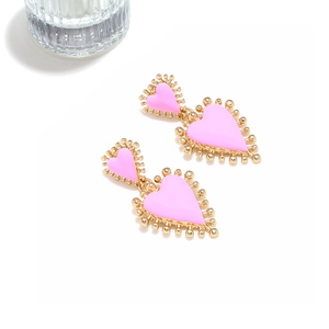 Detalle de pendientes de corazón en esmalte rosa con cuentas doradas en capas