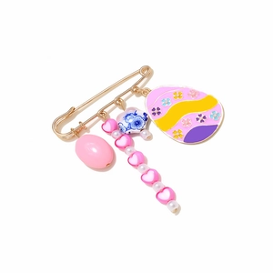 Golden Easter egg brooch with pink heart beads and enamel floral charm on white background