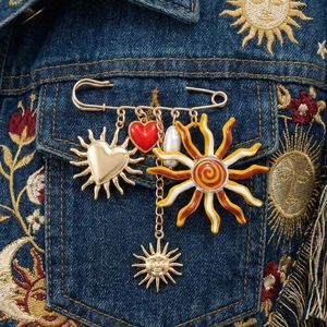 Golden sun and red heart charm safety pin brooch on embroidered blue denim jacket
