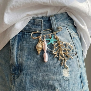 Broche baroque perle étoile de mer corail avec breloques dorées sur tissu denim