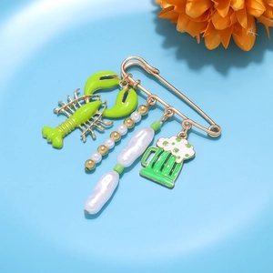 Detail of lobster, beer mug and baroque pearl charms on a golden safety pin brooch