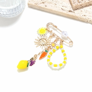 Exaggerated brooch with colorful lemon, carrot, daisy and pearl charms in golden finish