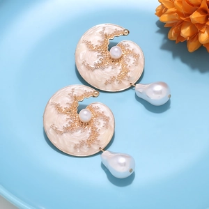 Macro detail of baroque pearl drop earrings with nautilus shell enamel and gold finish