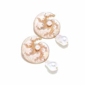 Macro shot of seashell-shaped enamel earrings with golden micro-beads and baroque pearls