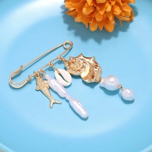 Detailed macro of ocean theme brooch with seashell and pearl charms on golden pin