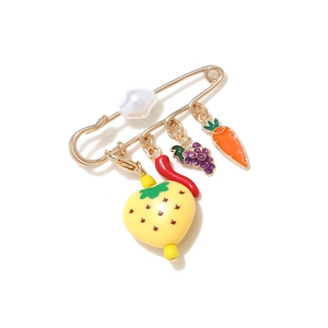 Detail of a gold-tone safety pin brooch with pearl and fruit enamel pendants