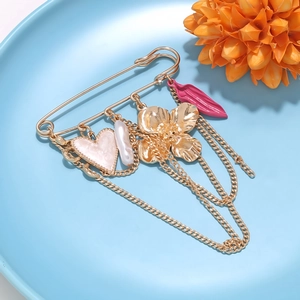 Détail de la broche épingle dorée avec breloques cœur rose, perle et fleur émaillée