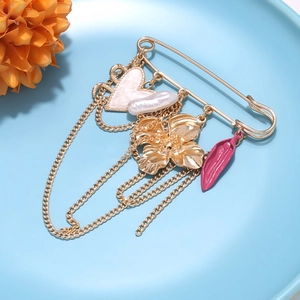 Vue détaillée d'une broche dorée avec breloques perle et cœur sur une assiette bleue