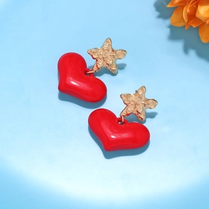Detailed shot of gold star and red heart earrings on a light blue background