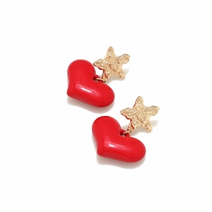 Macro detail of red heart earrings with textured golden star studs on white background