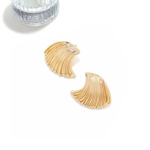 Detailed close-up of golden shell-shaped earrings with fine textured radial grooves