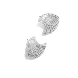 Macro detail of silver shell earrings showing textured relief and bright metallic luster