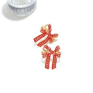 Detail of red enamel bow earrings with gold finish and vibrant polka dot textures
