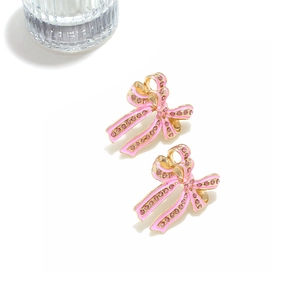 Detail of pink enamel bow earrings with sparkling rhinestones on golden alloy base