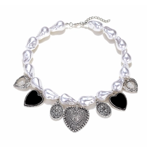 Collier en perles baroques avec pendentifs cœur noirs et argentés sur fond blanc