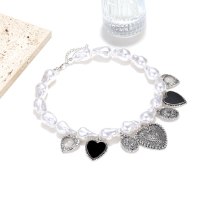 Collier en perles baroques avec pendentifs cœur noir et argent sur fond blanc pur