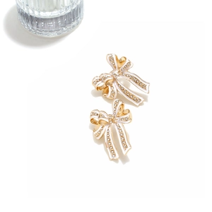Close-up of enamel bow earrings with sparkling crystals and gold-plated metal finish