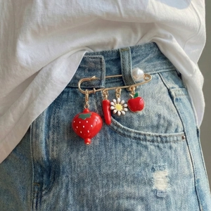 Cute strawberry and pepper multi-charm safety pin brooch worn on light denim jeans