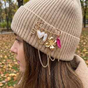 Broche dorée vintage avec breloques cœur et fleurs sur un bonnet en maille beige