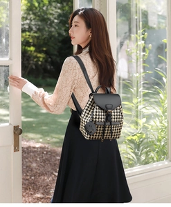 Detail of houndstooth backpack with black leather trim and cute smiley face charm