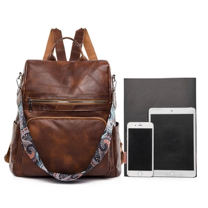 Deep brown faux leather backpack with jacquard strap shown with laptop for size reference