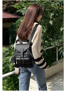 Detail view of black quilted backpack featuring a drawstring closure and smiley charm